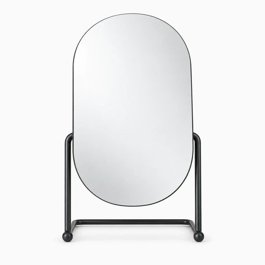 Miroir ovale doré avec monture métallique fine posé sur une surface plane